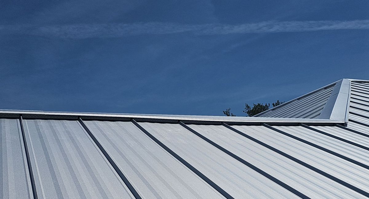 Light gray standing seam metal panels against a blue sky